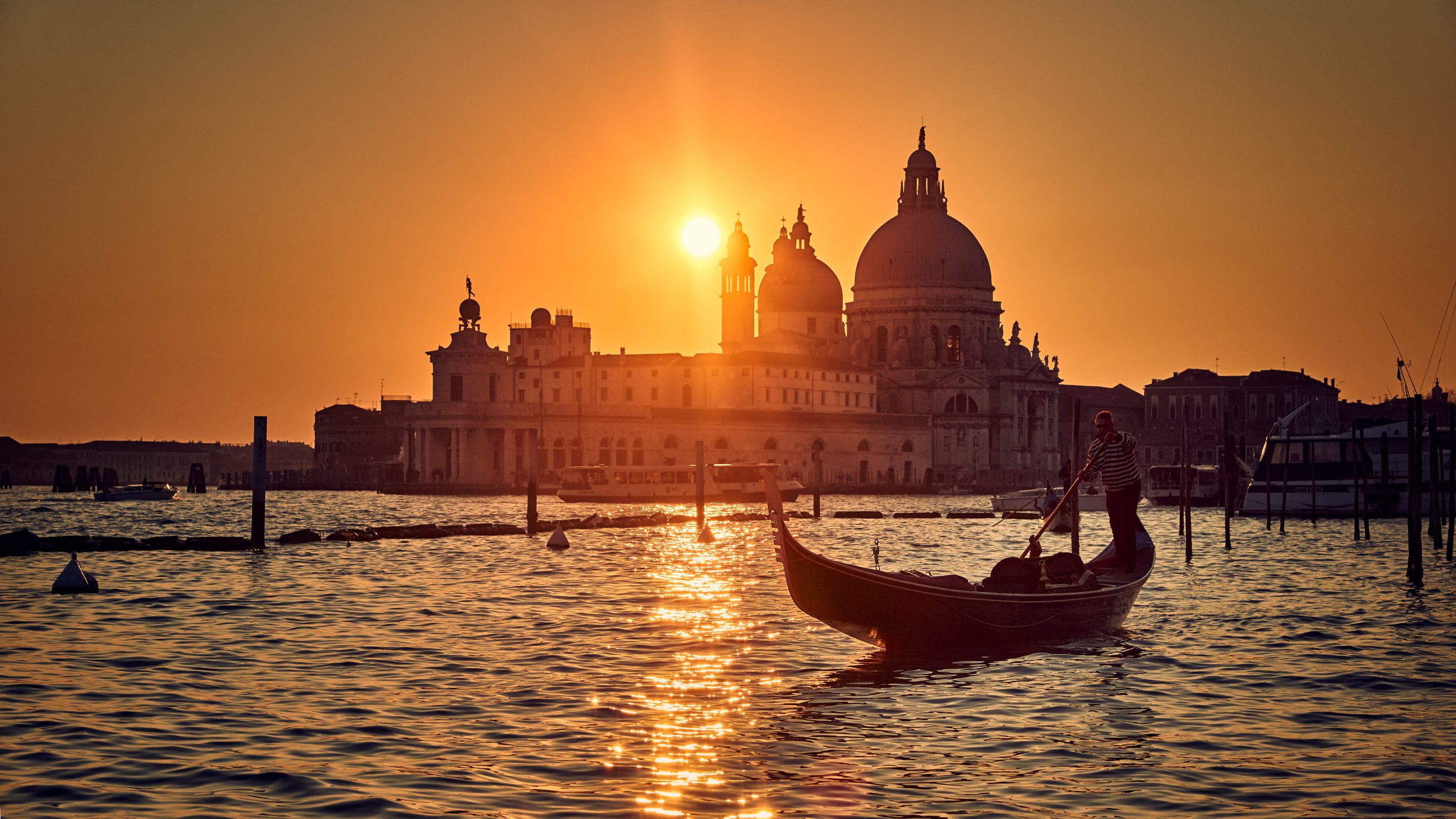 Puesta de sol en un góndolo de pie en su góndola en Venecia